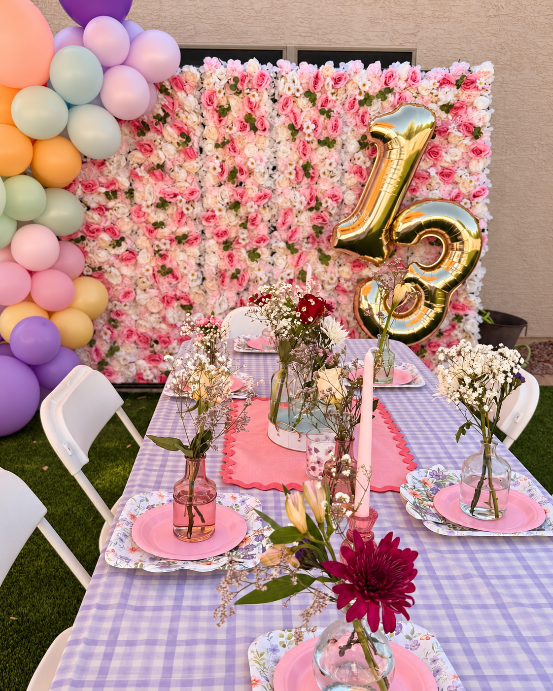 Sassy Party Decor birthday setting with pastel balloons, a pink flower wall, gold 13 balloons and lavender table styling.